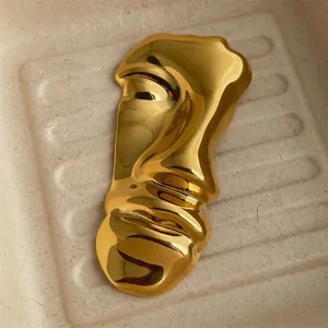 Macro view of abstract gold face brooch featuring mirror-polished molten texture