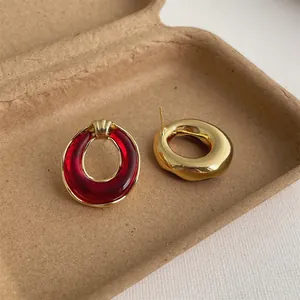 Detail eines roten Harz-Ohrrings und goldenen Metallreifens auf Vintage-Papier