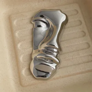 Detailed macro view of the silver abstract face brooch with a high-polished mirror finish