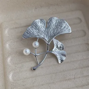 Détail de la broche feuille de ginkgo argentée avec perles et texture en métal brossé