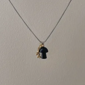 Detailed view of creative black mushroom pendant with golden beads on box chain
