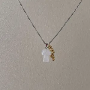 Detailed shot of pink mushroom pendant and gold bead clusters on a silver box chain