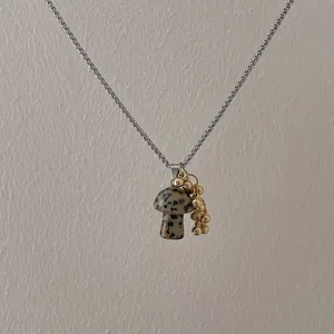 Detailed close-up of a spotted mushroom pendant on a silver-tone long sweater chain