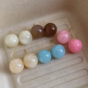 Macro detail van vijf paar marmeren hars oorknopjes in diverse zachte pastelkleuren