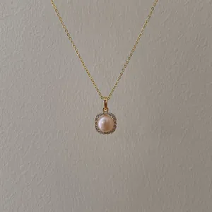 Macro view of gold chain with pink pearl pendant surrounded by sparkling crystals