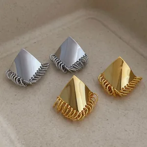 Detail of geometric rhombus tassel earrings in polished gold and silver finishes