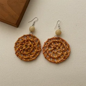 Detailed close-up of handmade woven rattan earrings with cream beads and silver hooks