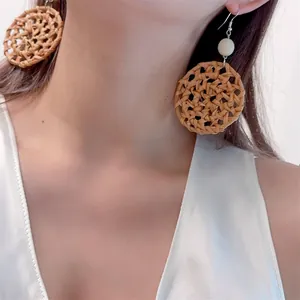 Close-up of bohemian rattan woven hoop earrings with white beads on a model