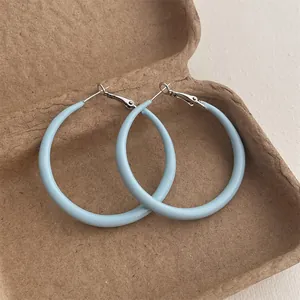 Close-up of light blue lacquer hoop earrings in a vintage box with silver clasp detail