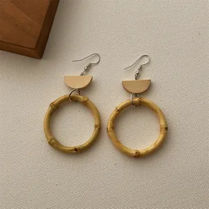 Close-up of bohemian handmade woven rattan earrings with natural wood semi-circle