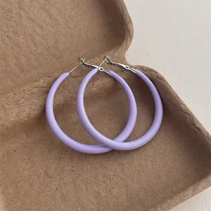 Close-up of lilac purple oversized matte hoop earrings on a textured paper box