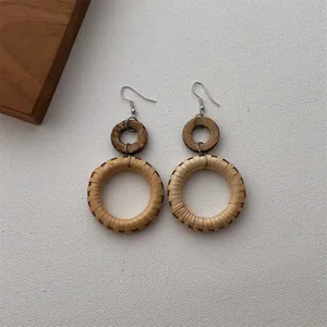 Close-up of bohemian rattan woven earrings with dark wood rings on white fabric