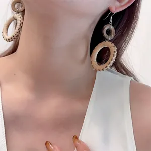 Close-up of bohemian woven rattan hoop earrings with wood texture on a female model
