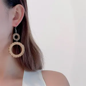 Close-up of bohemian woven rattan hoop earrings with wood accent on model's ear