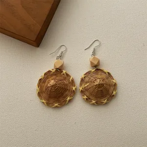 Detail of handmade woven straw hat earrings with wooden beads in bohemian style