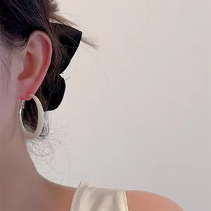 Macro shot of a cream-colored hoop earring worn by a model with a stylish bow