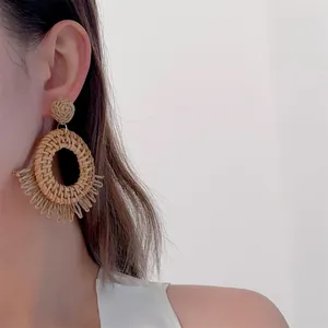 Detail showing handmade raffia woven earrings with tassels in a bohemian beach style