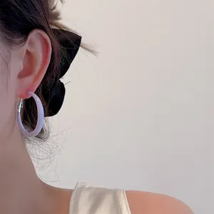 Close-up of model wearing thick lavender hoop earrings with sleek resin finish