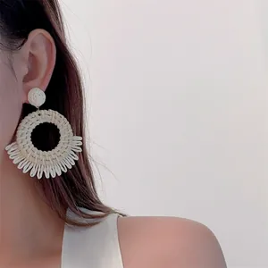 Close-up of handmade raffia woven hoop earrings with fringe in bohemian style