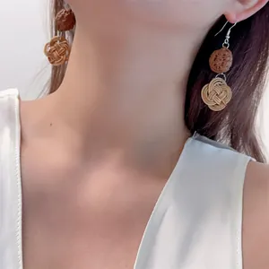 Close-up of bohemian rattan woven drop earrings on a model for a vintage summer look
