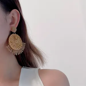 Detailed view of handmade raffia tassel earrings on model for bohemian beach style