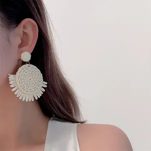 Detailed texture of handmade raffia woven earrings with bohemian fringe tassels