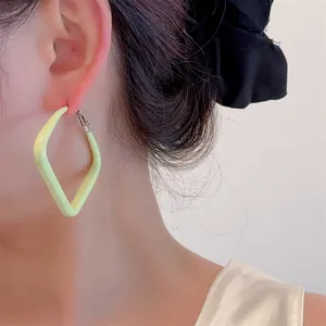 Side view of model wearing a light yellow geometric rhombus matte finish earring