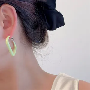 Close-up of minimalist square hoop earring in pale yellow lacquer on a model