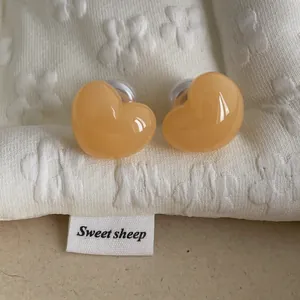 Macro shot of apricot heart stud earrings with glossy finish on floral texture