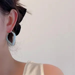 Close-up of a minimalist light blue square earring worn by a model in soft lighting