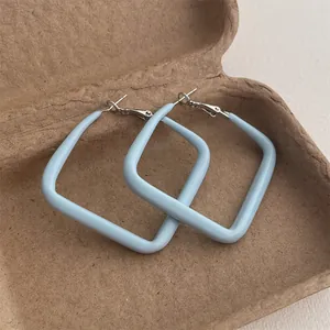 Detail of square light blue geometric hoop earrings with a matte lacquer finish in a gift box