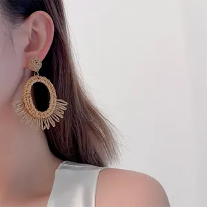 Detail of bohemian handmade straw earrings featuring natural woven oval fiber texture
