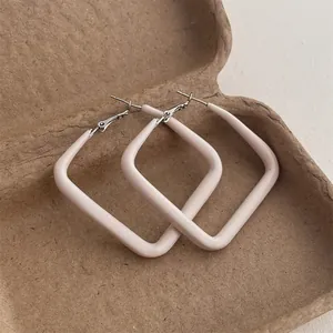 Detail of square geometric hoop earrings with cream enamel finish and stud closure