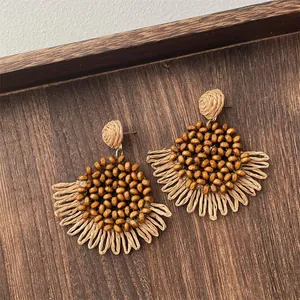 Macro detail of natural wooden beads and hand-woven raffia fan fringe earrings