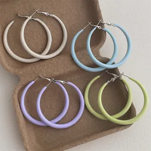 Close-up of candy-colored matte resin hoop earrings in cream, blue, purple, and green