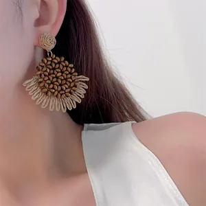 Macro detail of bohemian raffia woven earrings with wood beads and straw tassels