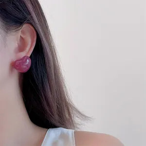 Close-up of pink heart-shaped resin earring on model's ear with marble texture