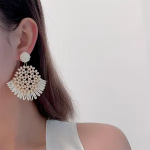 Close-up of bohemian woven raffia earrings with wooden beads on model ear