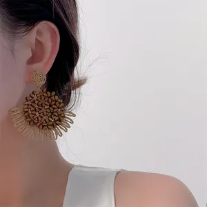 Detail of bohemian raffia woven earrings with wood bead center and sunburst petal design