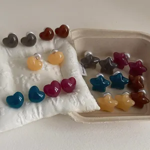 Detail of candy-colored heart and star earrings with faux pearl backings on display
