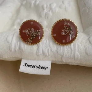 Detailed macro view of vintage resin earrings with dried flowers and tiny white pearls