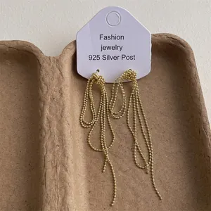 Detailed view of long gold tassel earrings with beaded chains on a jewelry display card