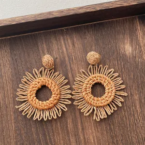 Close-up of handmade raffia woven hoop earrings with sunflower-shaped bohemian texture