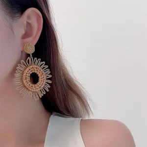 Close-up of handmade raffia sunflower earrings with bohemian straw woven details