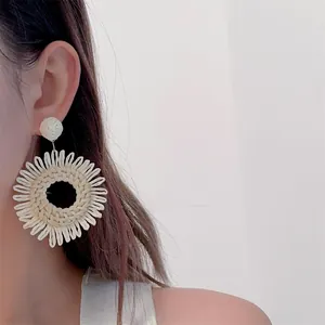 Close-up of handmade round raffia earrings on model for bohemian beach style look