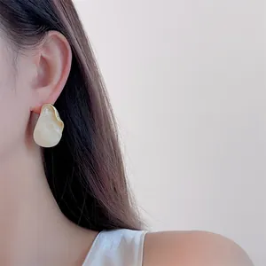 Close-up of marble resin stud earring with gold metal trim worn by a model