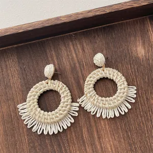 Detailed macro shot of bohemian cream raffia woven earrings on a rustic wood background