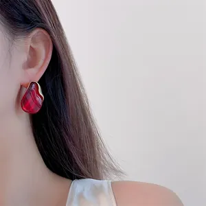 Close-up of amber resin drop earring with gold metal trim worn by model