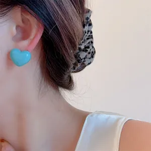 Close-up of bright turquoise heart earrings on model for a trendy summer look