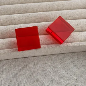 Detail of red acrylic square stud earrings showing transparent geometric cube design